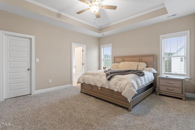 bedroom featuring ceiling fan, light carpet, ensuite bath, and a tray ceiling