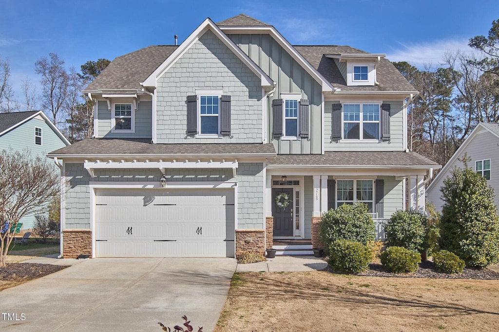craftsman-style home featuring an attached garage, stone siding, driveway, and a shingled roof