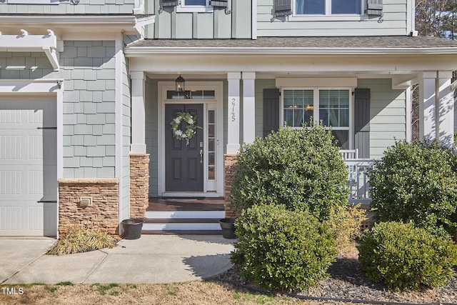 property entrance with a garage, stone siding, roof with shingles, and board and batten siding