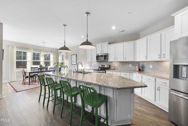 kitchen with white cabinets, a kitchen island with sink, appliances with stainless steel finishes, and sink