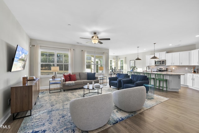 living room with ceiling fan, sink, and light hardwood / wood-style flooring