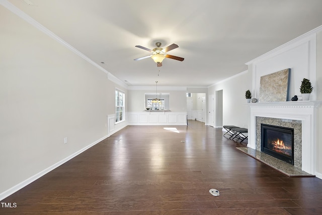 unfurnished living room with dark wood-type flooring, a high end fireplace, ornamental molding, and ceiling fan