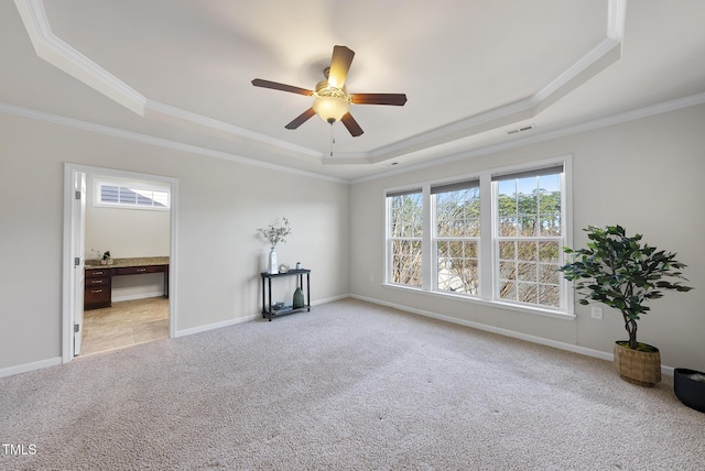 carpeted empty room with ceiling fan, ornamental molding, and a tray ceiling