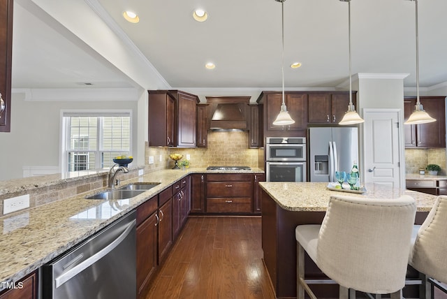 kitchen featuring sink, a breakfast bar area, light stone counters, stainless steel appliances, and custom range hood