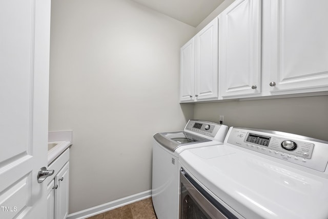 washroom with cabinets, washer and dryer, and dark tile patterned floors