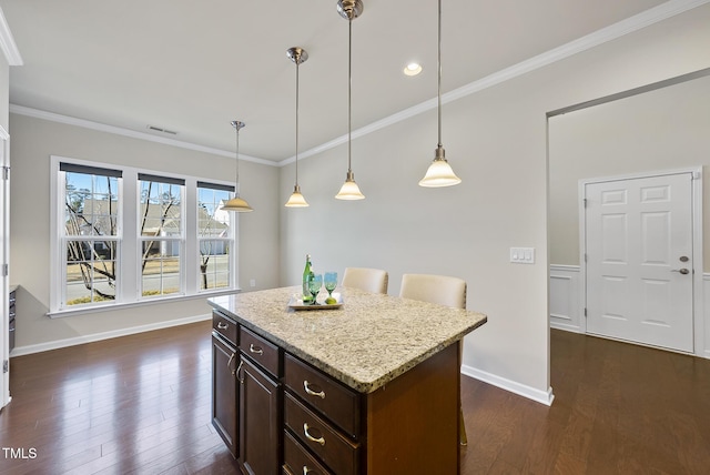 kitchen with crown molding, a breakfast bar, a center island, and hanging light fixtures