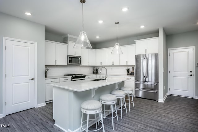 kitchen with hanging light fixtures, white cabinetry, sink, and appliances with stainless steel finishes