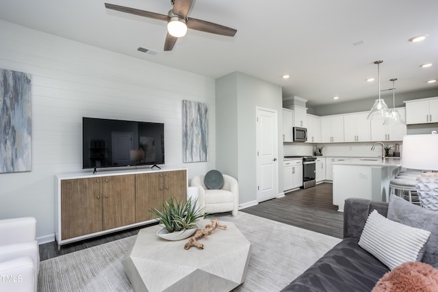 living room with ceiling fan, sink, and dark hardwood / wood-style floors