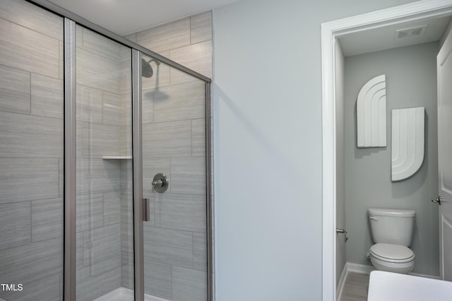 bathroom featuring toilet and a shower with shower door