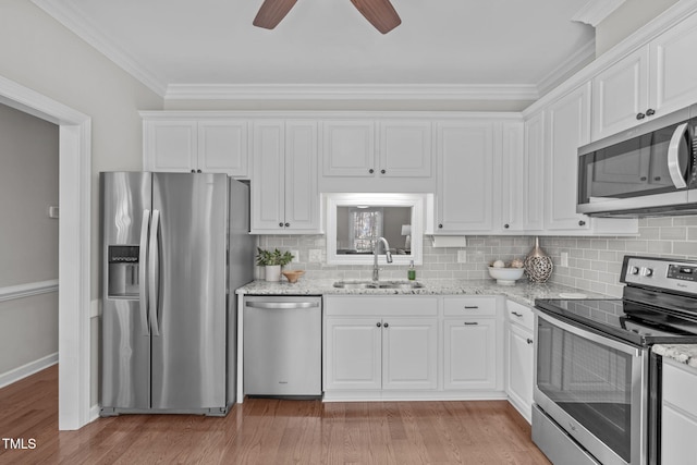 kitchen with appliances with stainless steel finishes, white cabinetry, light hardwood / wood-style floors, and sink