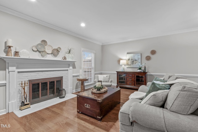 living room with a fireplace, crown molding, and light hardwood / wood-style flooring