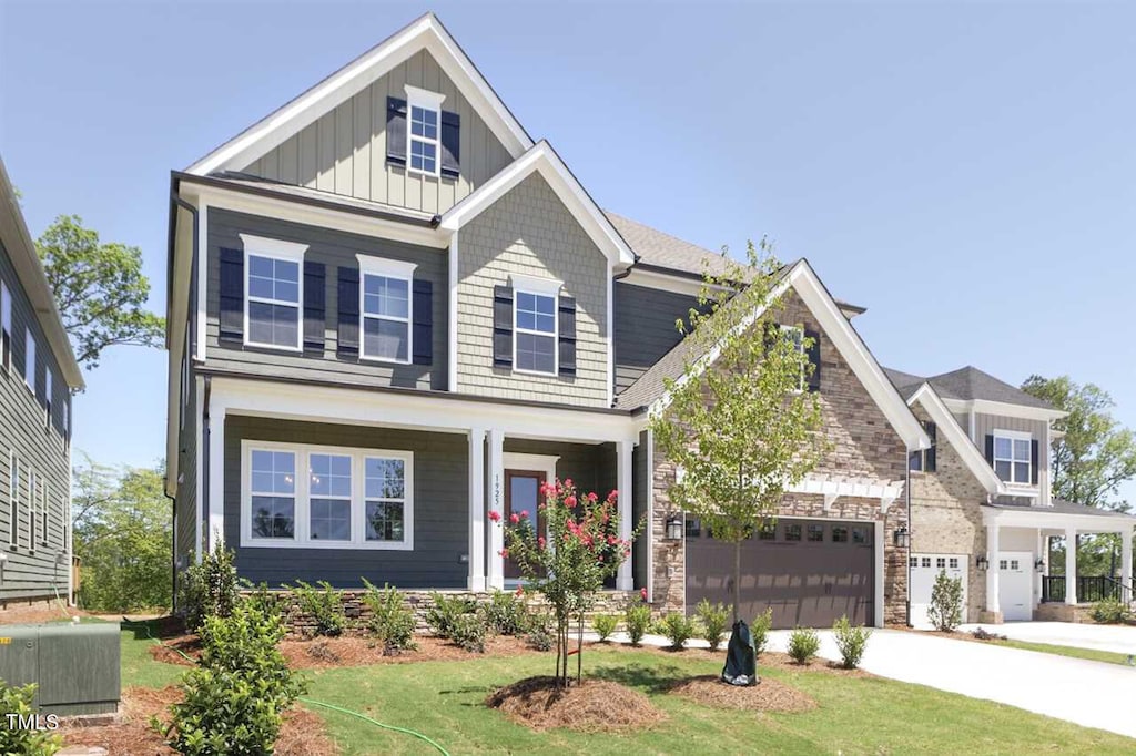 craftsman-style house featuring central AC unit, a front lawn, and a garage