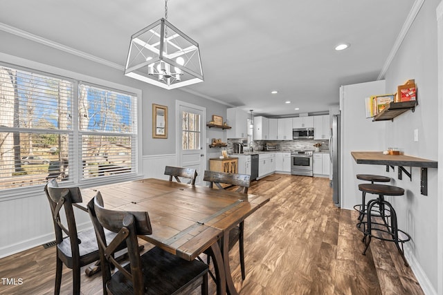 dining room featuring hardwood / wood-style flooring, ornamental molding, plenty of natural light, and a notable chandelier