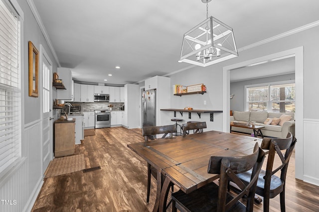 dining area with dark hardwood / wood-style flooring, ornamental molding, a chandelier, and sink