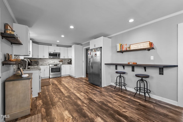 kitchen featuring appliances with stainless steel finishes, white cabinets, kitchen peninsula, backsplash, and dark wood-type flooring