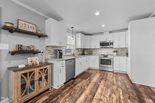 kitchen featuring pendant lighting, stainless steel appliances, decorative backsplash, white cabinets, and sink