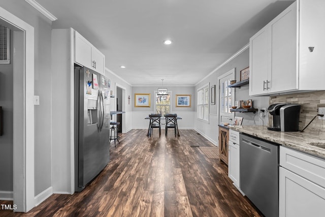 kitchen with white cabinetry, ornamental molding, light stone counters, and appliances with stainless steel finishes