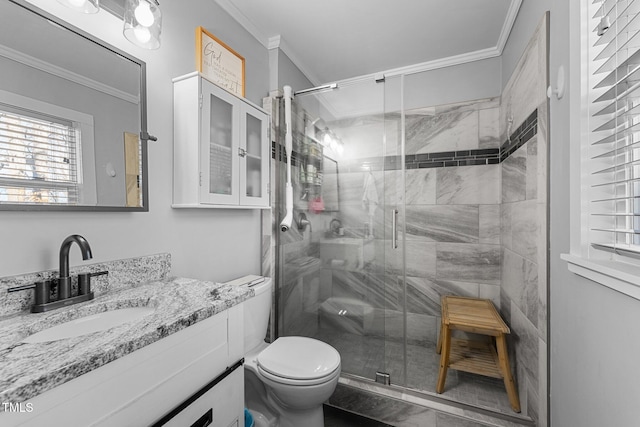 bathroom featuring toilet, vanity, a shower with shower door, and crown molding