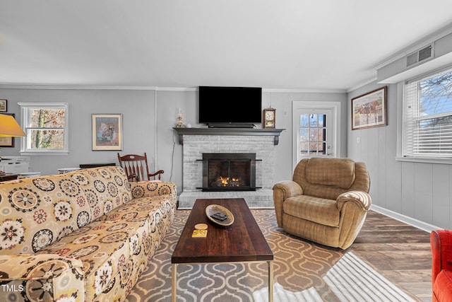 living room with ornamental molding, dark wood-type flooring, and a brick fireplace