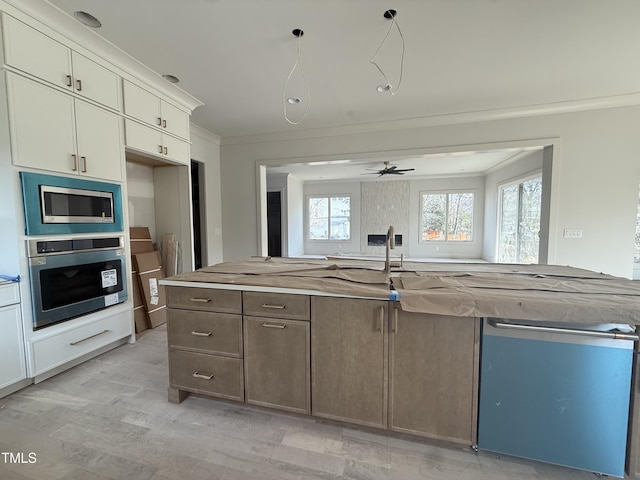 kitchen with crown molding, appliances with stainless steel finishes, a center island with sink, and cream cabinetry