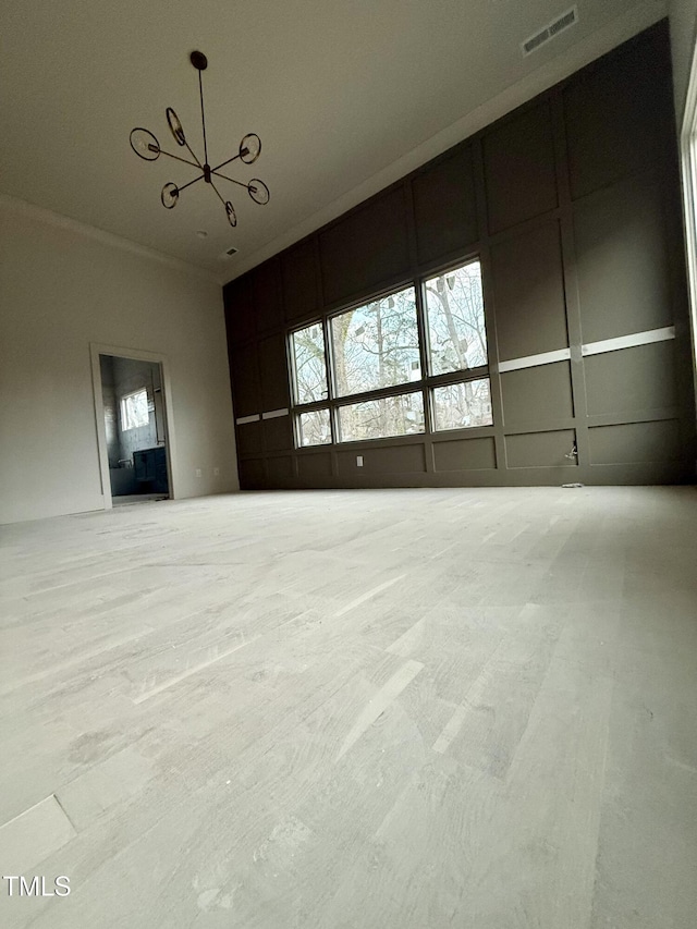 interior space featuring a notable chandelier, crown molding, a wealth of natural light, and a towering ceiling