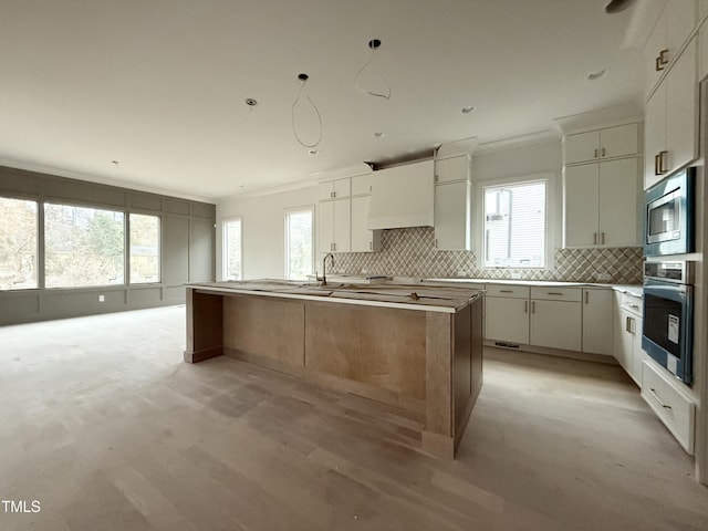 kitchen with a kitchen island, appliances with stainless steel finishes, custom range hood, and decorative backsplash