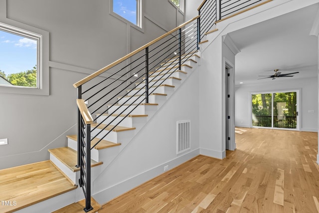 stairway featuring wood finished floors, a ceiling fan, and baseboards