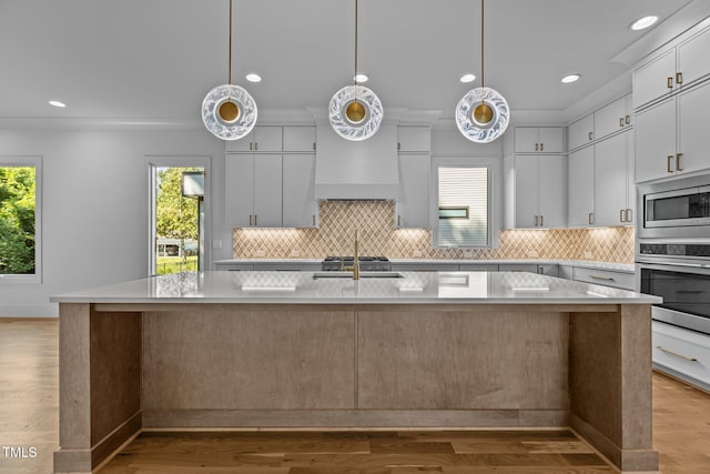 kitchen with stainless steel appliances, light countertops, tasteful backsplash, an island with sink, and recessed lighting