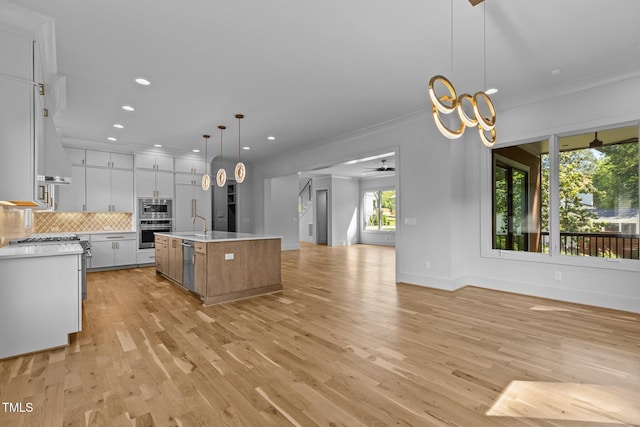 kitchen featuring appliances with stainless steel finishes, open floor plan, ornamental molding, light countertops, and backsplash