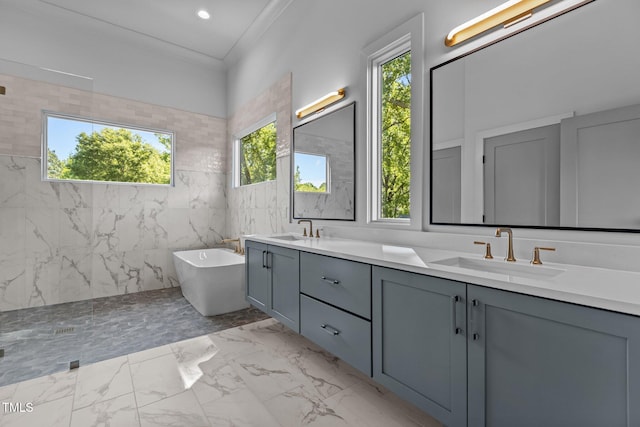 full bathroom with marble finish floors, double vanity, a freestanding bath, tile walls, and recessed lighting