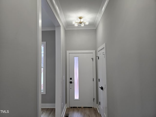 foyer entrance featuring wood-type flooring, a notable chandelier, and ornamental molding