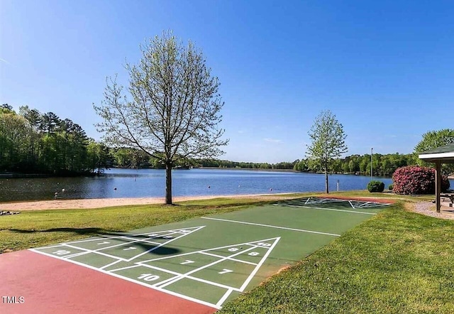 view of property's community with a lawn, shuffleboard, and a water view