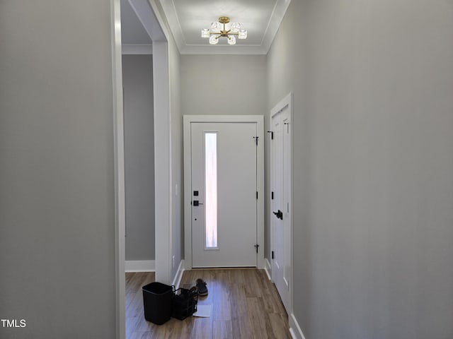 entryway featuring baseboards, an inviting chandelier, wood finished floors, and crown molding