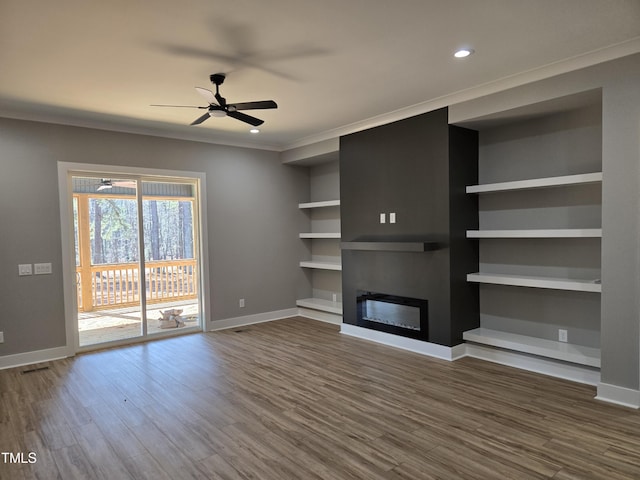 unfurnished living room with a glass covered fireplace, crown molding, baseboards, and dark wood-style flooring