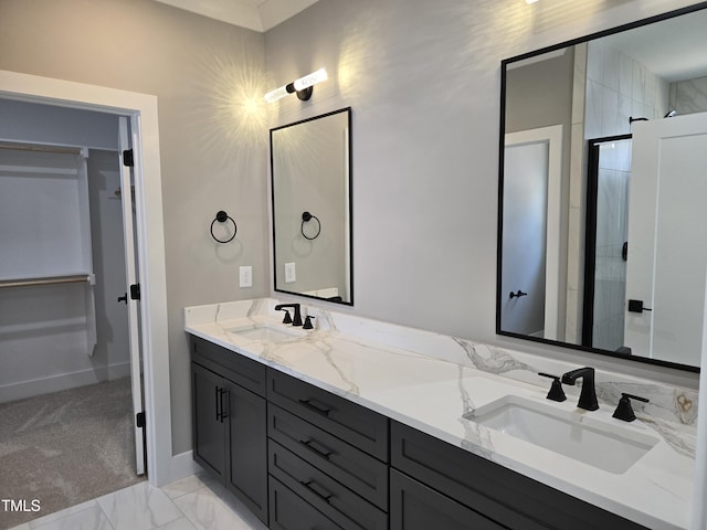 full bathroom featuring double vanity, marble finish floor, a walk in closet, and a sink