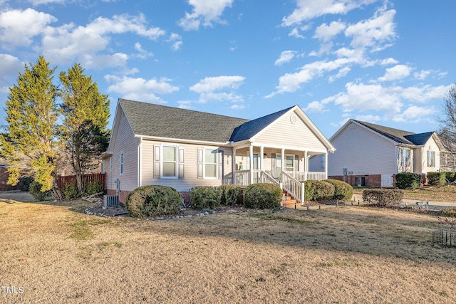 view of front of property featuring central air condition unit, a front lawn, and covered porch