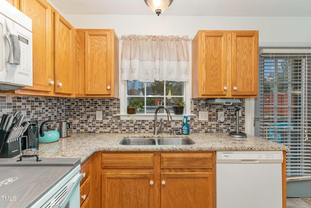 kitchen with sink, light stone counters, plenty of natural light, white appliances, and decorative backsplash