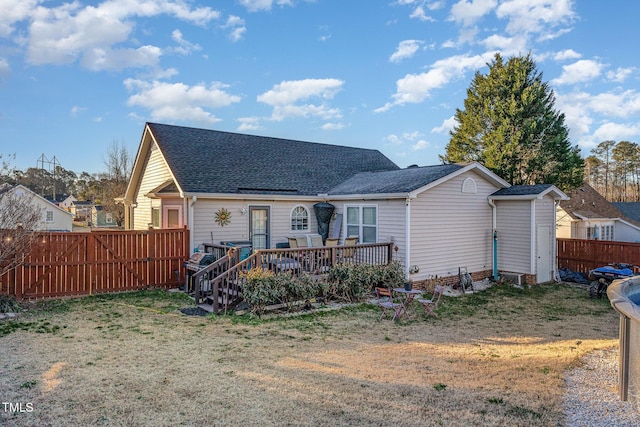 rear view of house featuring a wooden deck and a lawn