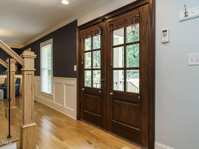 entrance foyer featuring a healthy amount of sunlight, light hardwood / wood-style flooring, french doors, and crown molding