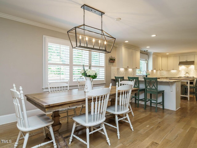 dining space featuring crown molding, light wood-type flooring, a wealth of natural light, and a chandelier