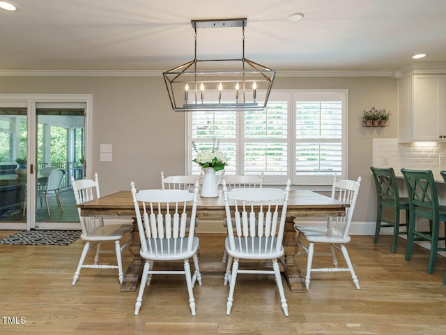 dining room with light hardwood / wood-style floors, a notable chandelier, and ornamental molding