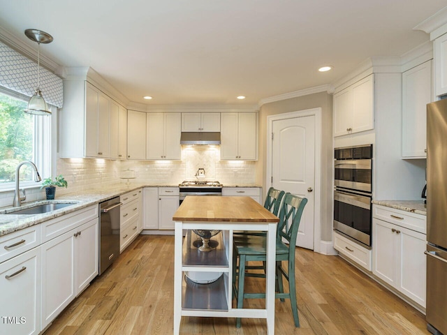 kitchen with sink, white cabinetry, hanging light fixtures, and appliances with stainless steel finishes