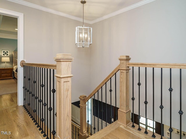 stairs with an inviting chandelier, hardwood / wood-style floors, and crown molding