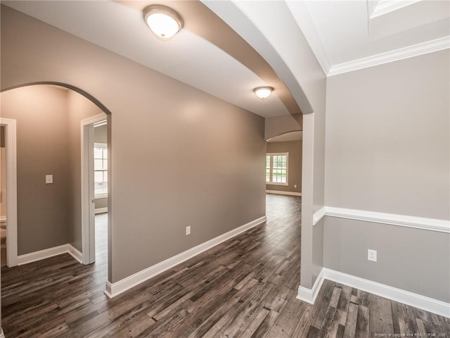 empty room with dark wood-type flooring and crown molding