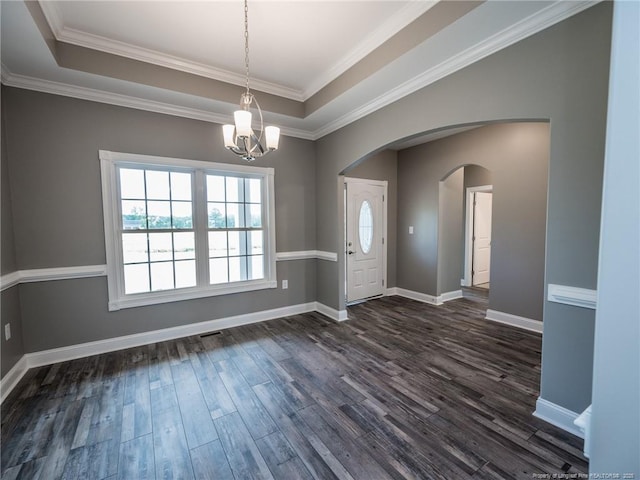 interior space featuring dark wood-type flooring, a raised ceiling, a notable chandelier, and ornamental molding