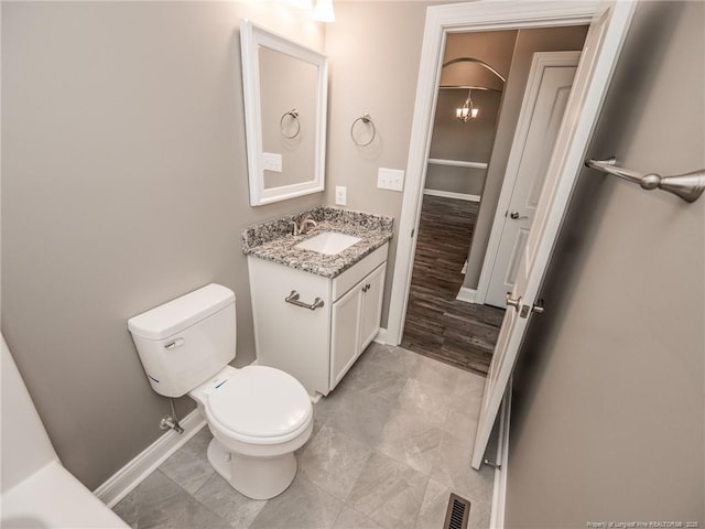 bathroom with toilet, vanity, and a chandelier