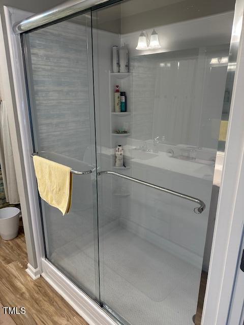 bathroom featuring a shower with shower door and hardwood / wood-style floors