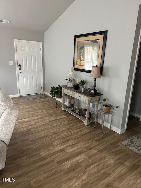 entrance foyer featuring vaulted ceiling and dark hardwood / wood-style floors