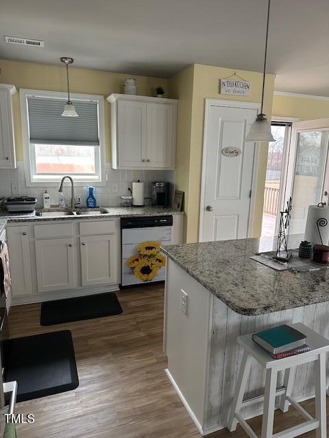 kitchen with white dishwasher, sink, decorative light fixtures, and white cabinets