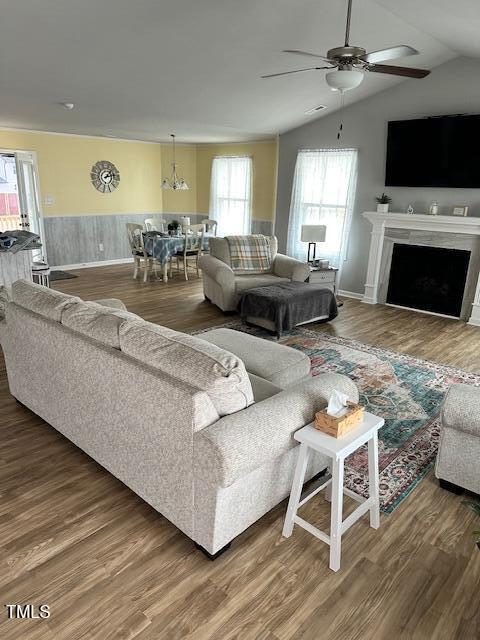 living room featuring lofted ceiling, hardwood / wood-style flooring, and ceiling fan with notable chandelier